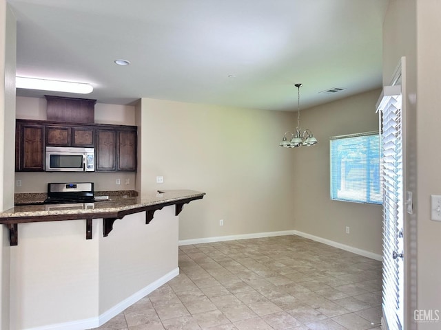 kitchen featuring dark brown cabinetry, decorative light fixtures, visible vents, a breakfast bar, and stainless steel appliances