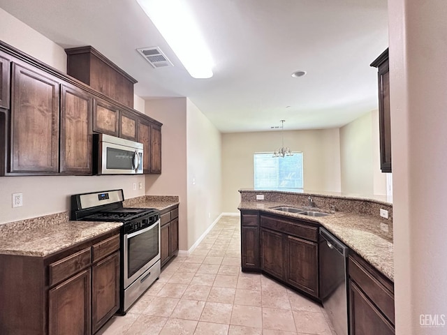 kitchen with visible vents, a peninsula, dark brown cabinets, a sink, and stainless steel appliances