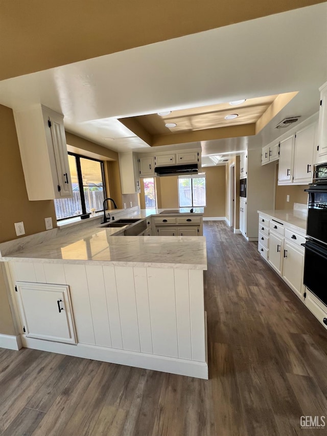 5306 Deville Ct, Bakersfield, CA 93308 - kitchen featuring a tray ceiling, a peninsula, dark wood finished floors, white cabinets, and light stone counters