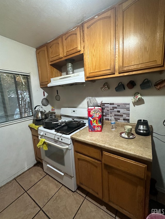 kitchen featuring light tile patterned floors and white gas range oven