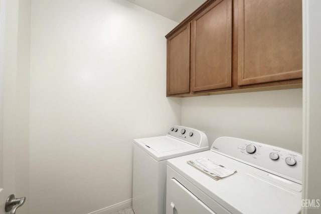 clothes washing area featuring cabinets and washer and clothes dryer