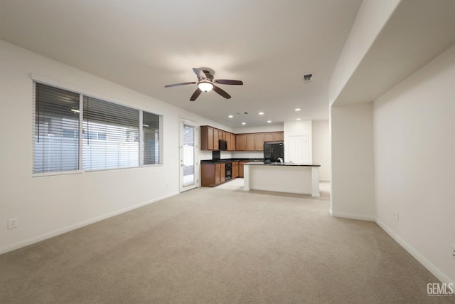 unfurnished living room featuring light colored carpet and ceiling fan