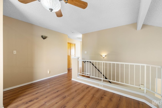 spare room featuring vaulted ceiling with beams, hardwood / wood-style floors, a textured ceiling, and ceiling fan