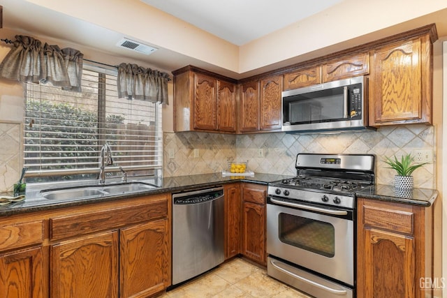 kitchen featuring tasteful backsplash, stainless steel appliances, sink, and dark stone countertops