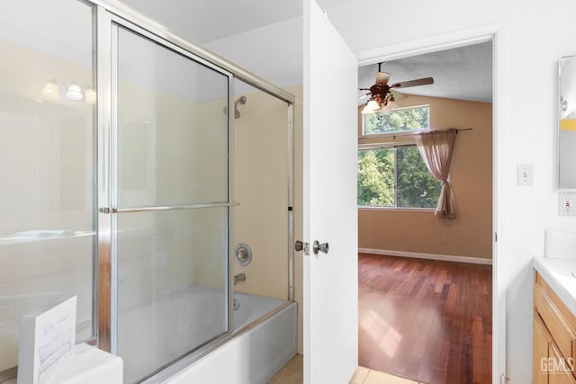 bathroom featuring lofted ceiling, enclosed tub / shower combo, ceiling fan, vanity, and a textured ceiling