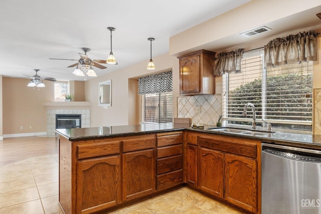 kitchen featuring sink, a tile fireplace, decorative backsplash, decorative light fixtures, and stainless steel dishwasher