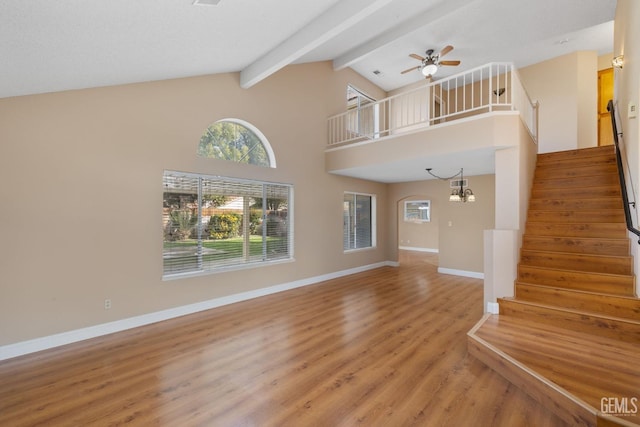 unfurnished living room with high vaulted ceiling, wood-type flooring, beam ceiling, and ceiling fan with notable chandelier