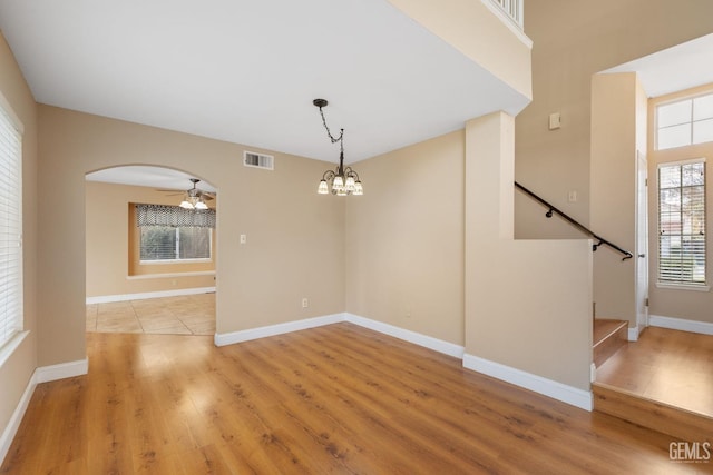 unfurnished room featuring ceiling fan with notable chandelier and light hardwood / wood-style flooring