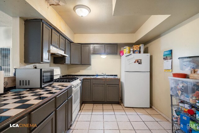 7901 Jay St, Lamont, CA 93241 - kitchen with a sink, under cabinet range hood, baseboards, light tile patterned floors, and white appliances