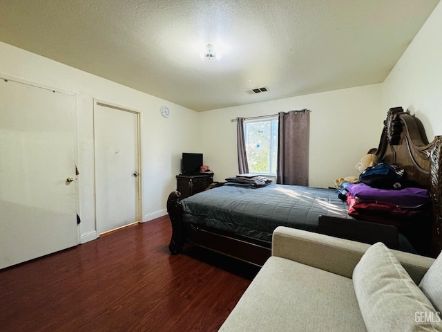 bedroom with a textured ceiling and dark hardwood / wood-style flooring