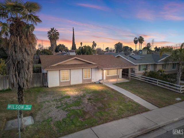 single story home featuring solar panels and a lawn