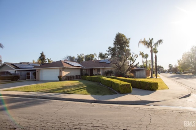 single story home with a garage, a front lawn, solar panels, and driveway