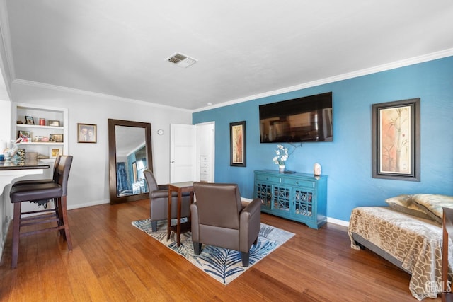 living room featuring crown molding, built in shelves, and hardwood / wood-style floors