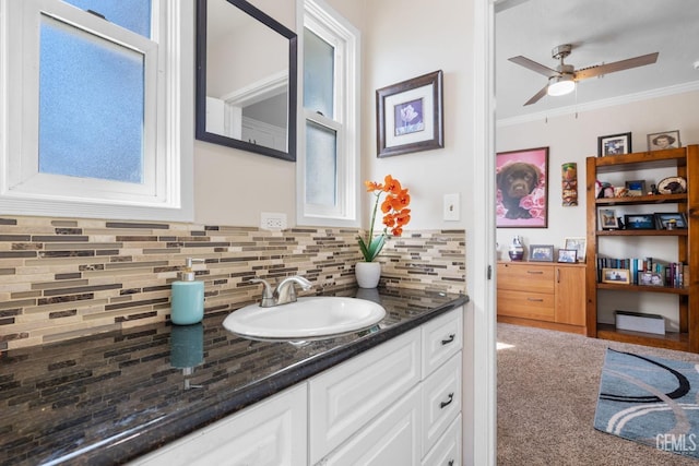 bathroom with ceiling fan, vanity, crown molding, and backsplash