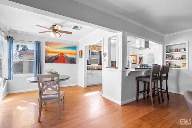 kitchen with light hardwood / wood-style floors, kitchen peninsula, white cabinetry, and a breakfast bar area