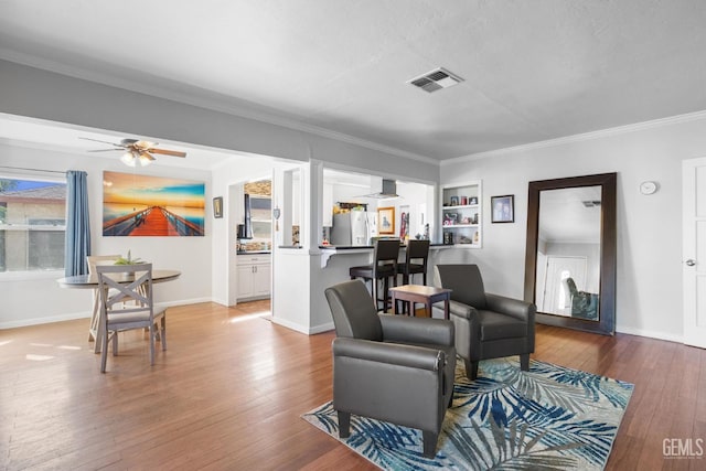 living room featuring ornamental molding, hardwood / wood-style floors, built in shelves, and ceiling fan