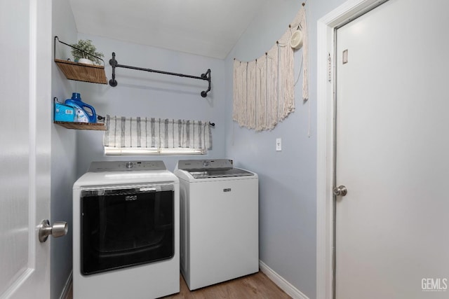 clothes washing area with baseboards, laundry area, washing machine and dryer, and light wood-style floors