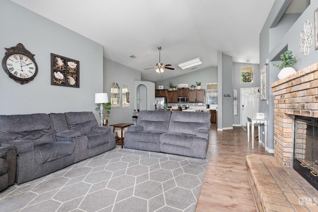 living area with baseboards, visible vents, a ceiling fan, light wood-style flooring, and a fireplace