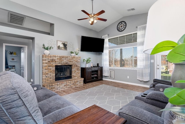 living room featuring lofted ceiling, a brick fireplace, wood finished floors, and visible vents