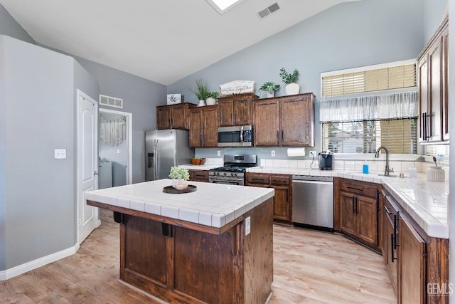 kitchen with stainless steel appliances, tile counters, visible vents, and a sink