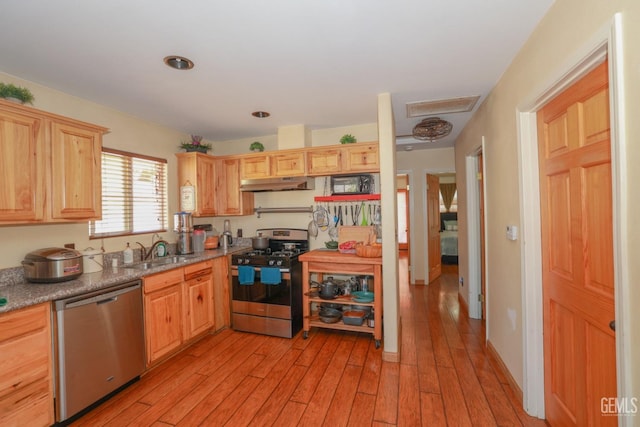 kitchen with sink, stainless steel appliances, light brown cabinets, and light hardwood / wood-style flooring