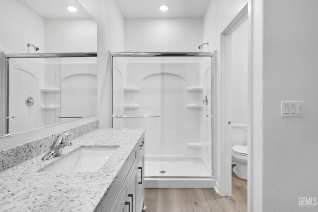 bathroom with wood-type flooring, vanity, walk in shower, and toilet