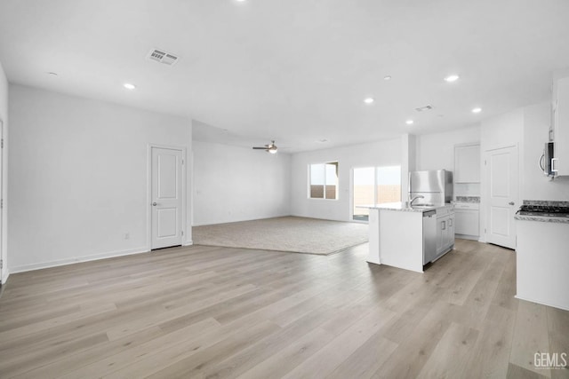 kitchen with a kitchen island with sink, stainless steel appliances, light hardwood / wood-style floors, and white cabinets