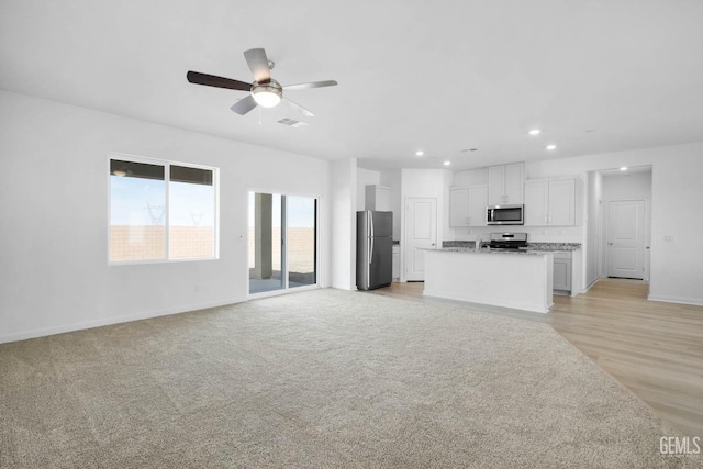 unfurnished living room featuring light colored carpet and ceiling fan