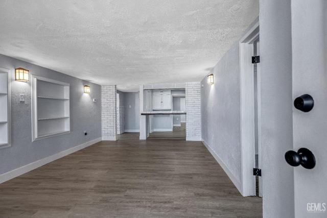 113 Lucard St, Taft, CA 93268 - unfurnished living room featuring built in features, a textured ceiling, dark wood-style floors, and baseboards