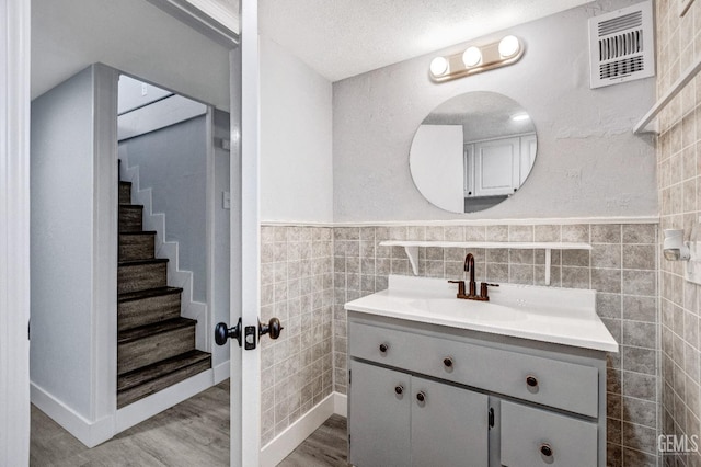 113 Lucard St, Taft, CA 93268 - bathroom featuring tile walls, vanity, wood finished floors, a wainscoted wall, and a textured ceiling