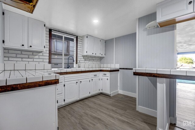 113 Lucard St, Taft, CA 93268 - kitchen featuring white cabinets, light wood-style flooring, tile countertops, a sink, and baseboards