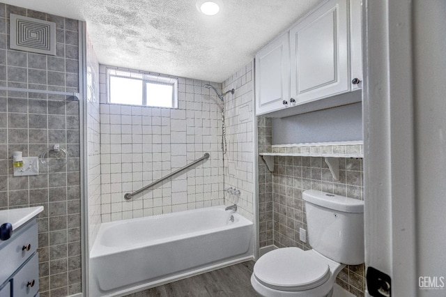 113 Lucard St, Taft, CA 93268 - bathroom with tile walls, a textured ceiling, wood finished floors, toilet, and washtub / shower combination