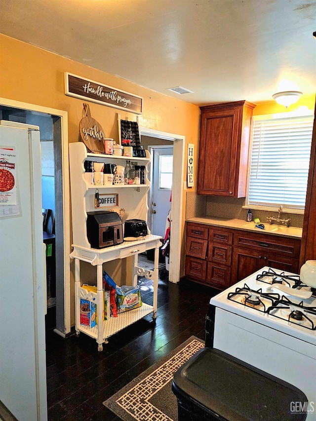 1806 Tulare St, Bakersfield, CA 93305 - kitchen featuring dark wood finished floors, light countertops, brown cabinetry, white appliances, and a sink