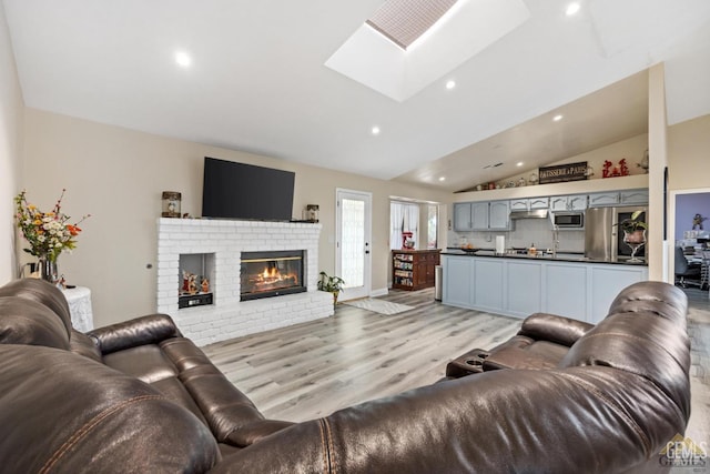 3105 Whisper Oak Way, Bakersfield, CA 93311 - living area featuring vaulted ceiling, a skylight, light wood-style flooring, recessed lighting, and a fireplace