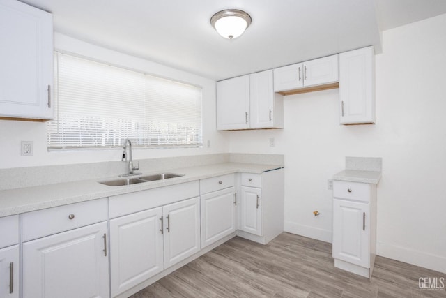 kitchen with white cabinets, light hardwood / wood-style flooring, and sink