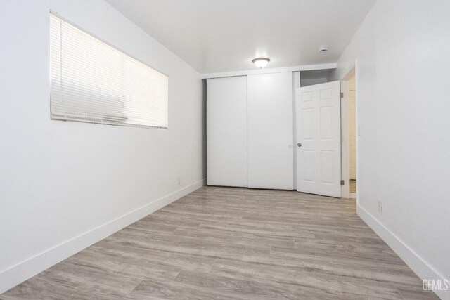 unfurnished bedroom with light hardwood / wood-style flooring and a closet