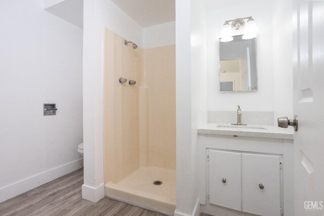 bathroom with a shower, hardwood / wood-style floors, vanity, and toilet