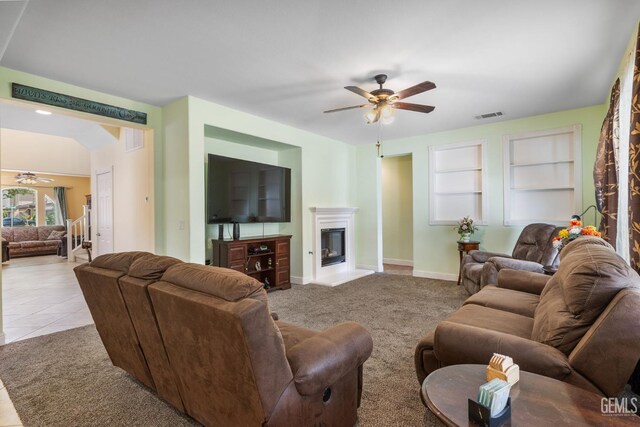 10114 Oporto Way, Bakersfield, CA 93306 - carpeted living room with a ceiling fan, built in shelves, a glass covered fireplace, and baseboards