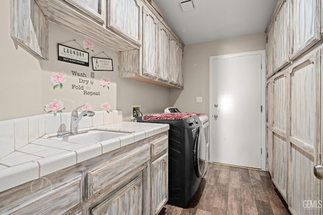 clothes washing area with sink, cabinets, dark wood-type flooring, and washer and clothes dryer