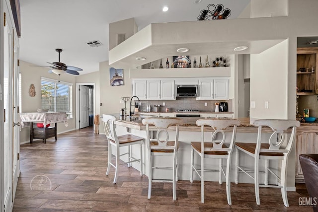 kitchen with sink, white cabinets, dark wood-type flooring, light stone counters, and decorative backsplash