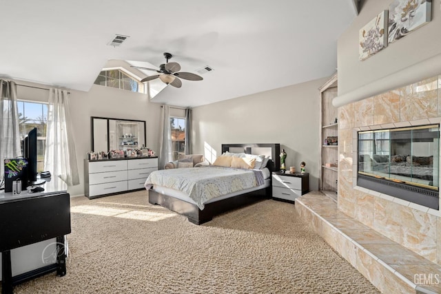 carpeted bedroom featuring ceiling fan, lofted ceiling, and a tiled fireplace