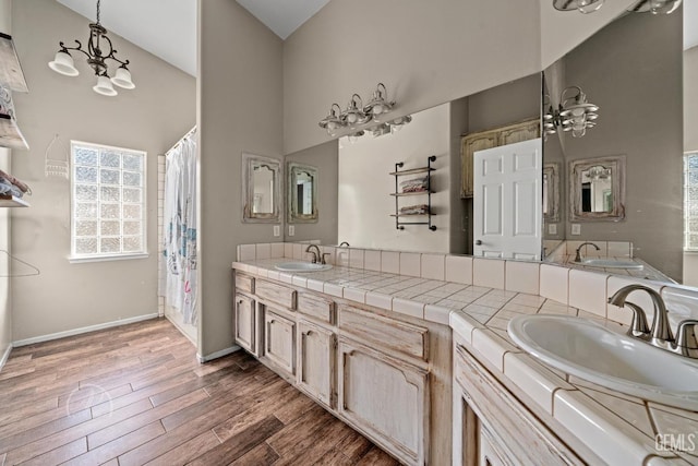 bathroom featuring vanity, a towering ceiling, a chandelier, and hardwood / wood-style floors