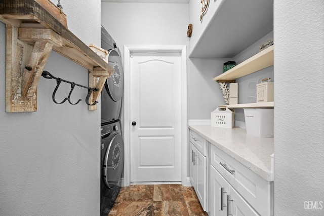 laundry area with cabinets and stacked washer / drying machine