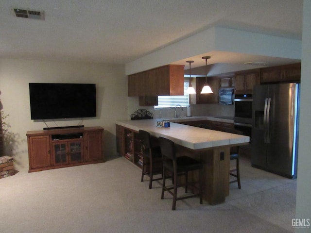 kitchen featuring sink, a kitchen breakfast bar, kitchen peninsula, pendant lighting, and stainless steel appliances