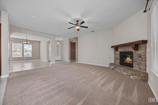 unfurnished living room featuring ceiling fan with notable chandelier, carpet, and a fireplace