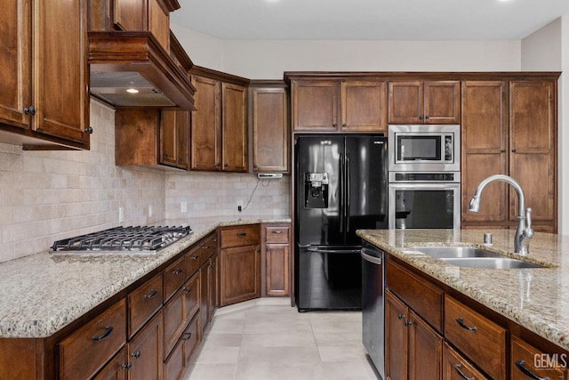 kitchen featuring backsplash, sink, light stone countertops, stainless steel appliances, and light tile patterned floors