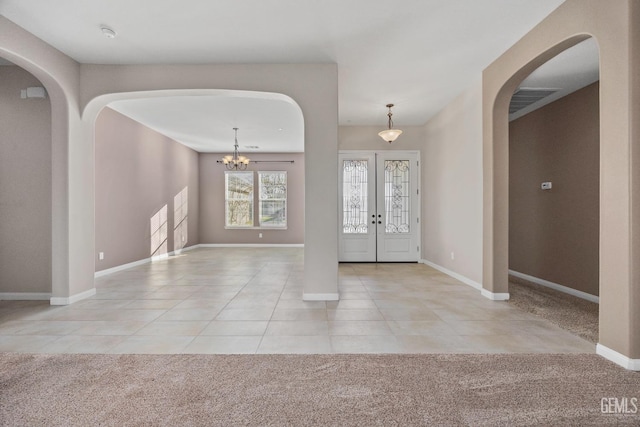 foyer entrance with light tile patterned floors, french doors, and an inviting chandelier