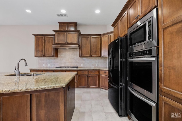 kitchen featuring light stone countertops, appliances with stainless steel finishes, exhaust hood, decorative backsplash, and sink