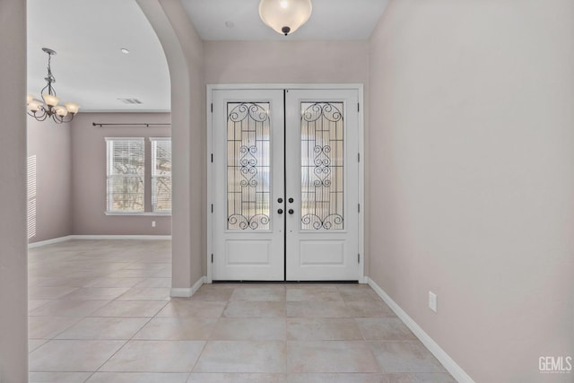 tiled entrance foyer featuring an inviting chandelier and french doors