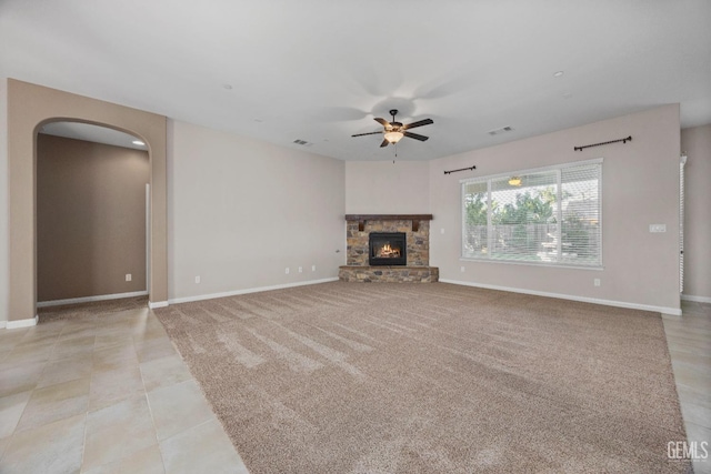 unfurnished living room with ceiling fan and a stone fireplace